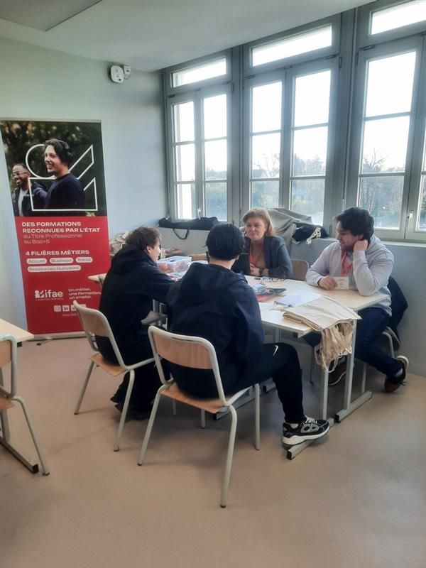 Personnes discutant autour d'une table dans une salle.