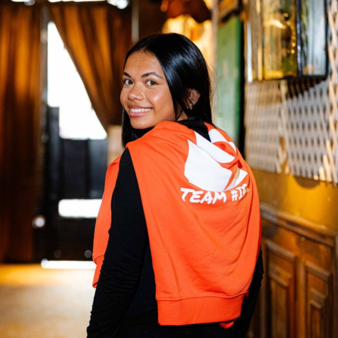 Femme souriante en sweat orange Team