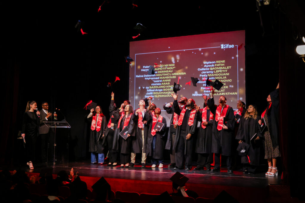 Des diplômés célèbrent la fin de leur parcours en lançant leurs toques en l’air. Un moment de fierté et de joie partagé sur scène.