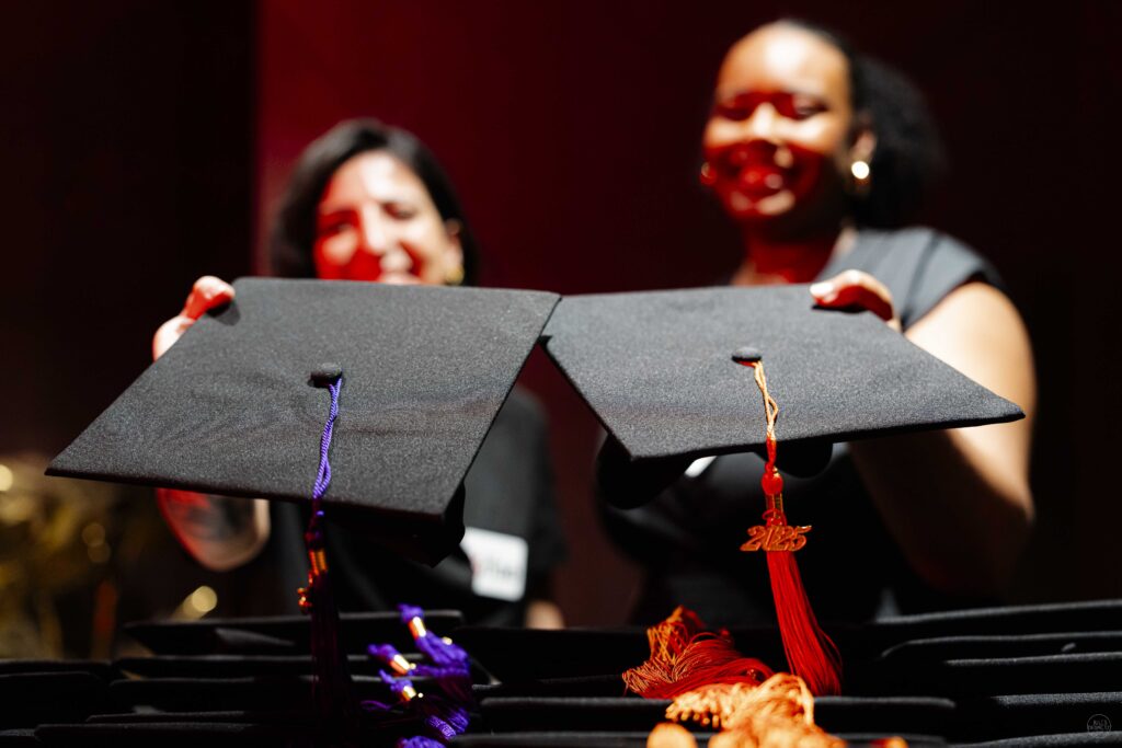 Deux personnes tenant des toques de diplômés.