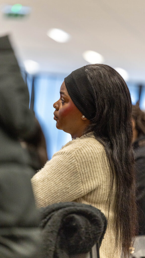 Personne assise en réunion, profil gauche visible.