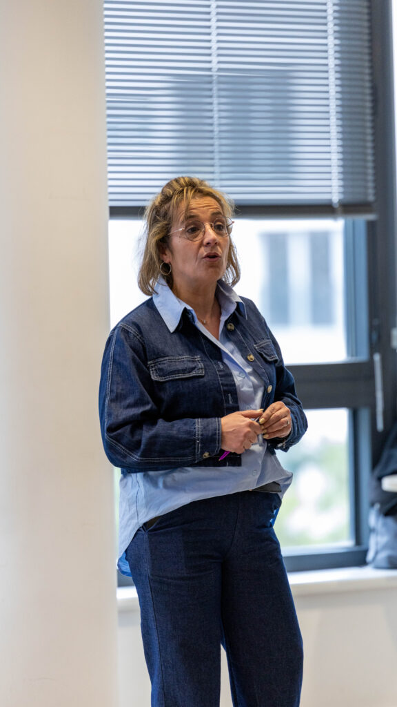 Femme en denim parle debout devant fenêtre.