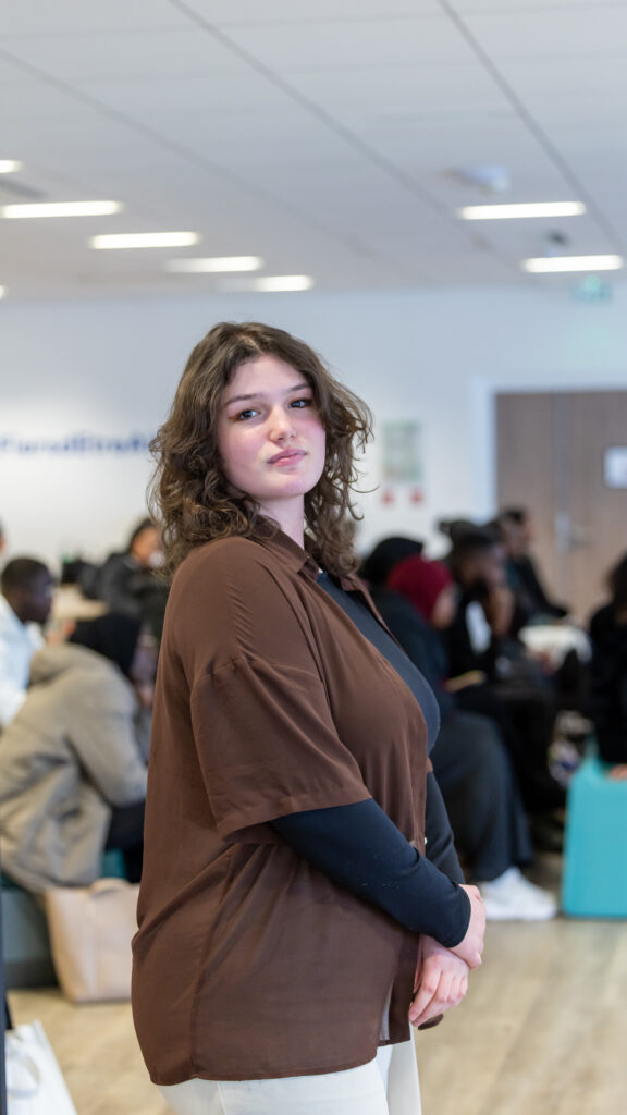 Femme debout, foule floue à l'arrière-plan.