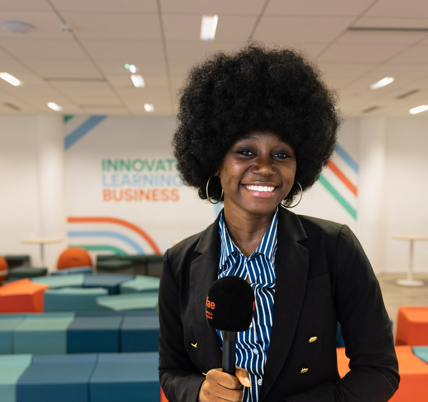 Journaliste souriante tenant un micro dans un espace collaboratif