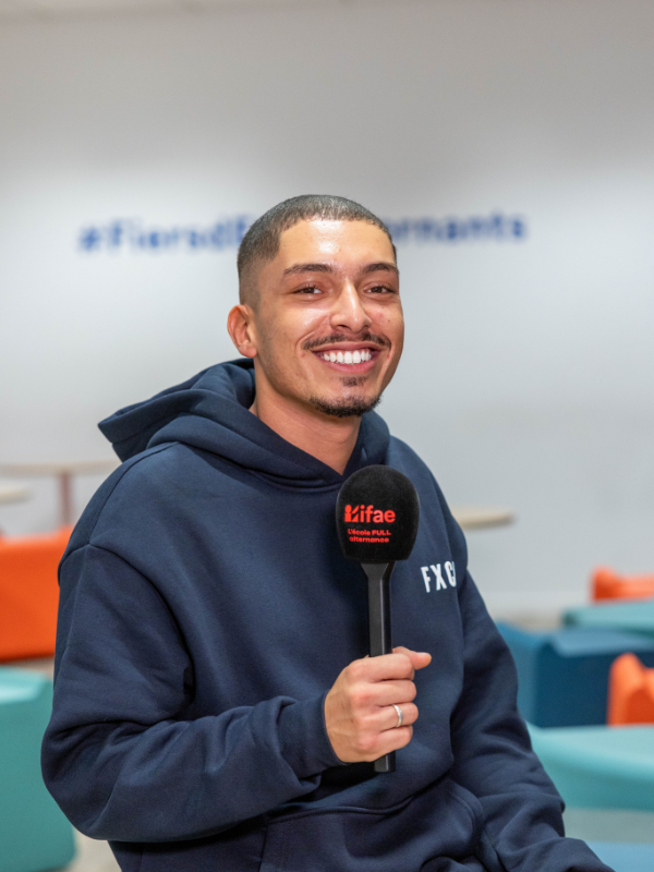 Homme souriant tenant un micro en intérieur