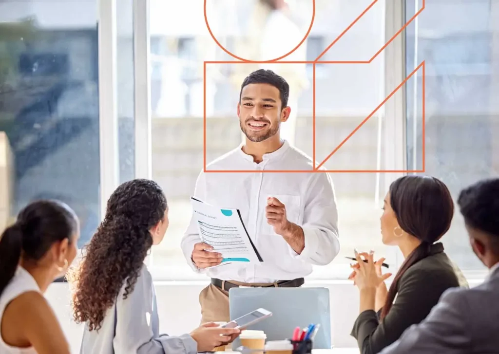 Réunion de travail entre collègues autour d'une table avec un responsable debout. le logo IFAE est autour du responsabe.