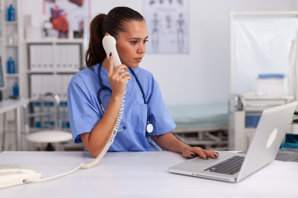 Secrétaire médicale au téléphone utilisant un ordinateur portable